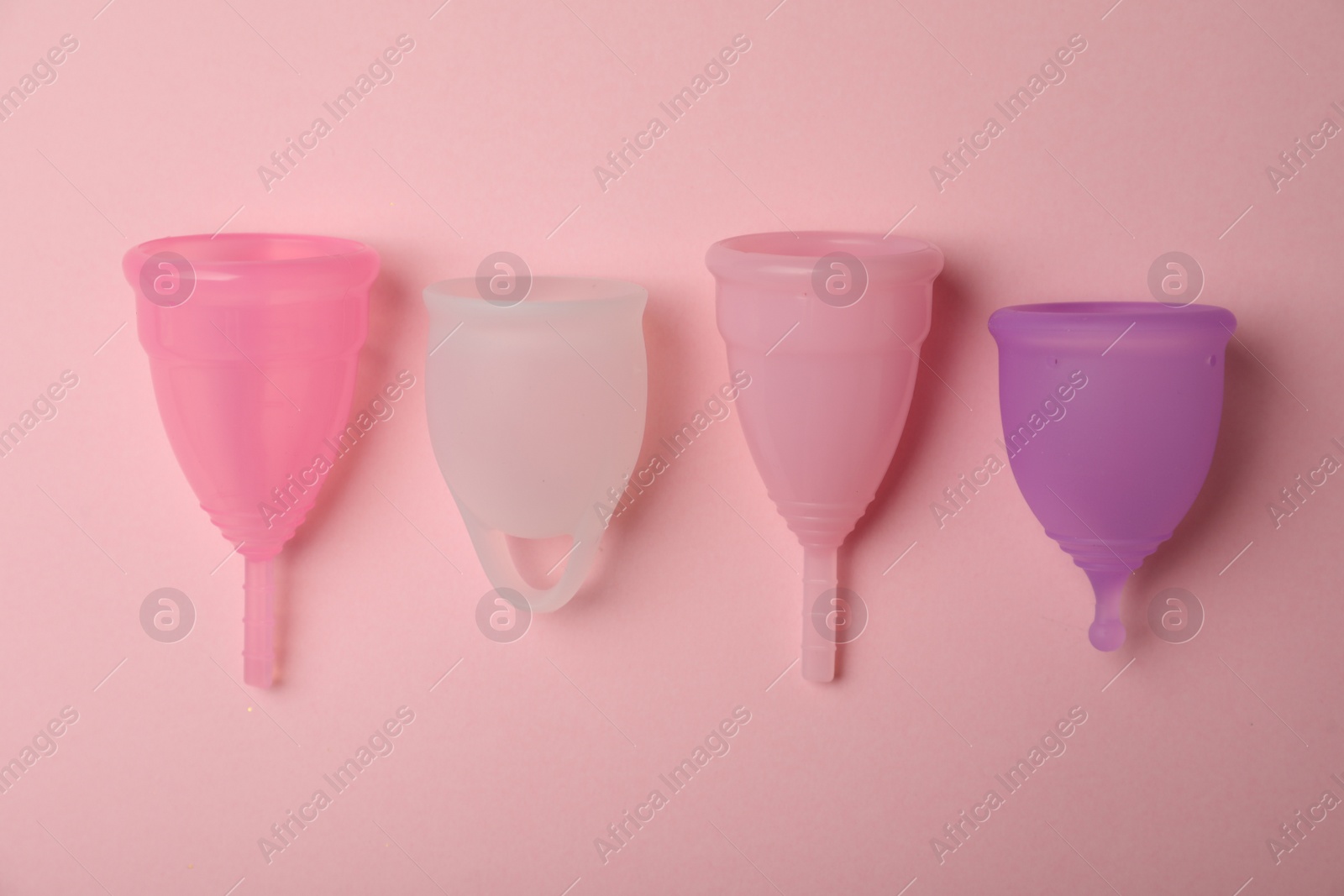 Photo of Different menstrual cups on pink background, flat lay