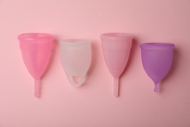 Different menstrual cups on pink background, flat lay