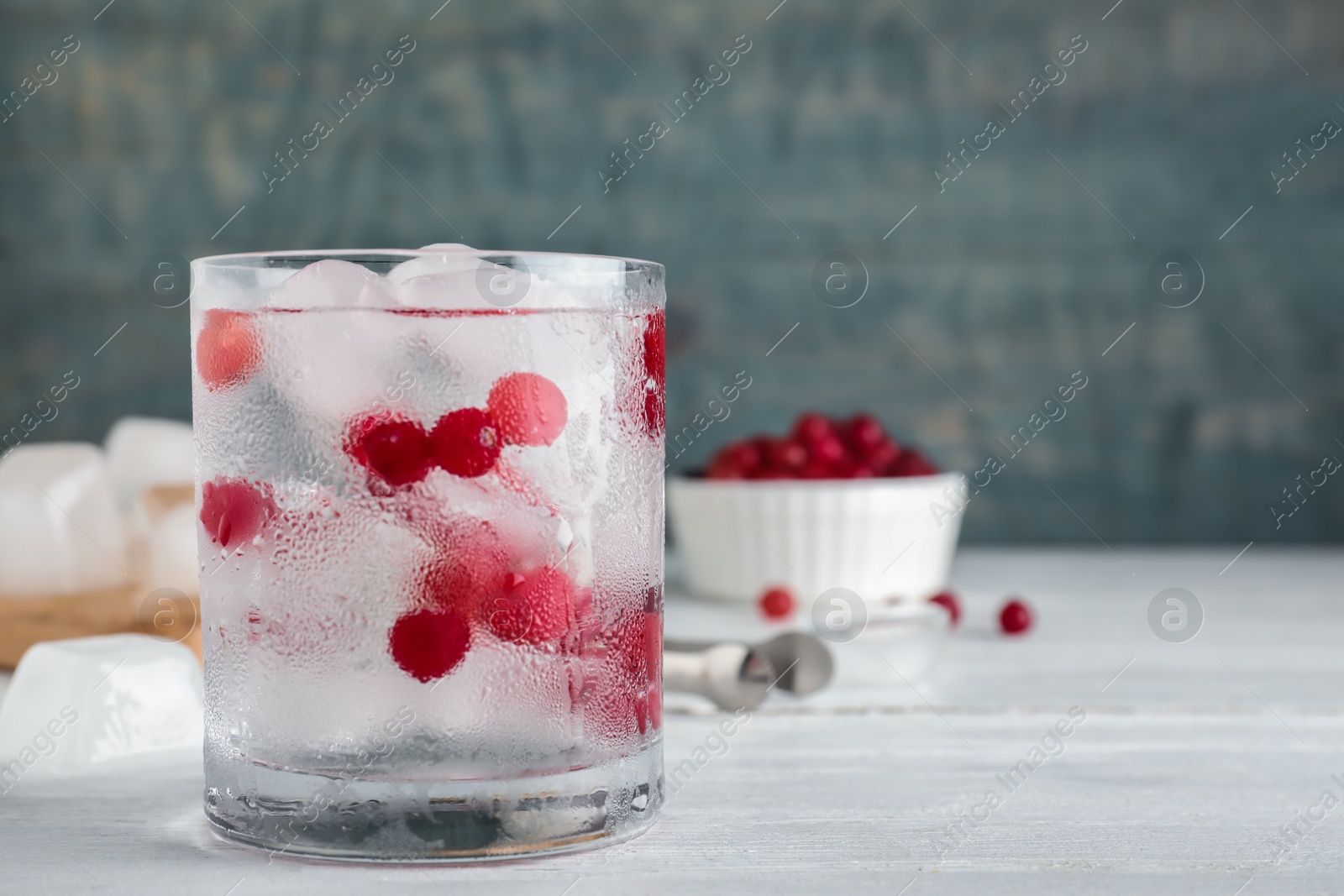 Photo of Glass of cocktail with vodka, ice and cranberry on wooden background. Space for text