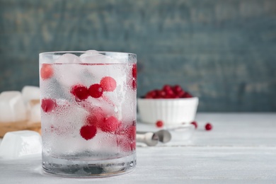 Glass of cocktail with vodka, ice and cranberry on wooden background. Space for text