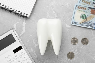 Flat lay composition with ceramic model of tooth and money on grey table. Expensive treatment