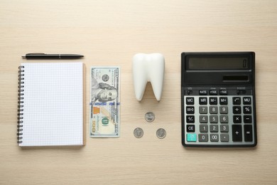 Flat lay composition with ceramic model of tooth and money on wooden table. Expensive treatment
