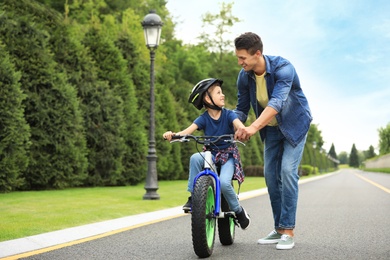 Dad teaching son to ride bicycle outdoors