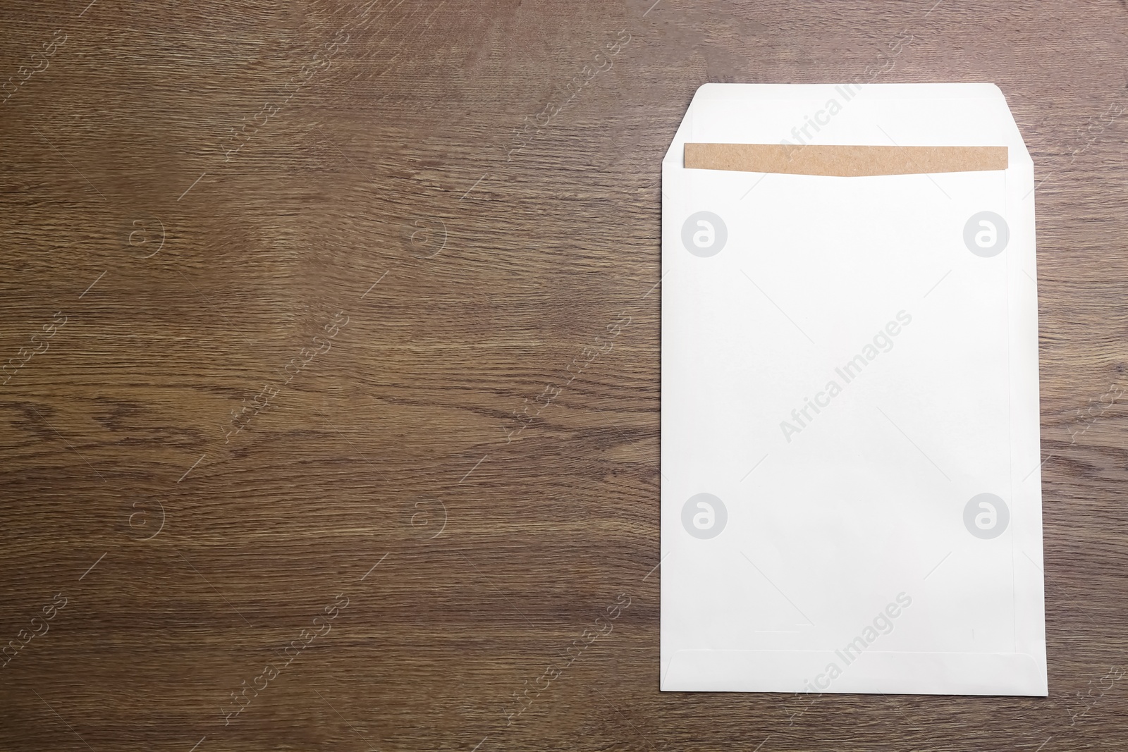Photo of White paper envelope on wooden background, top view. Space for text