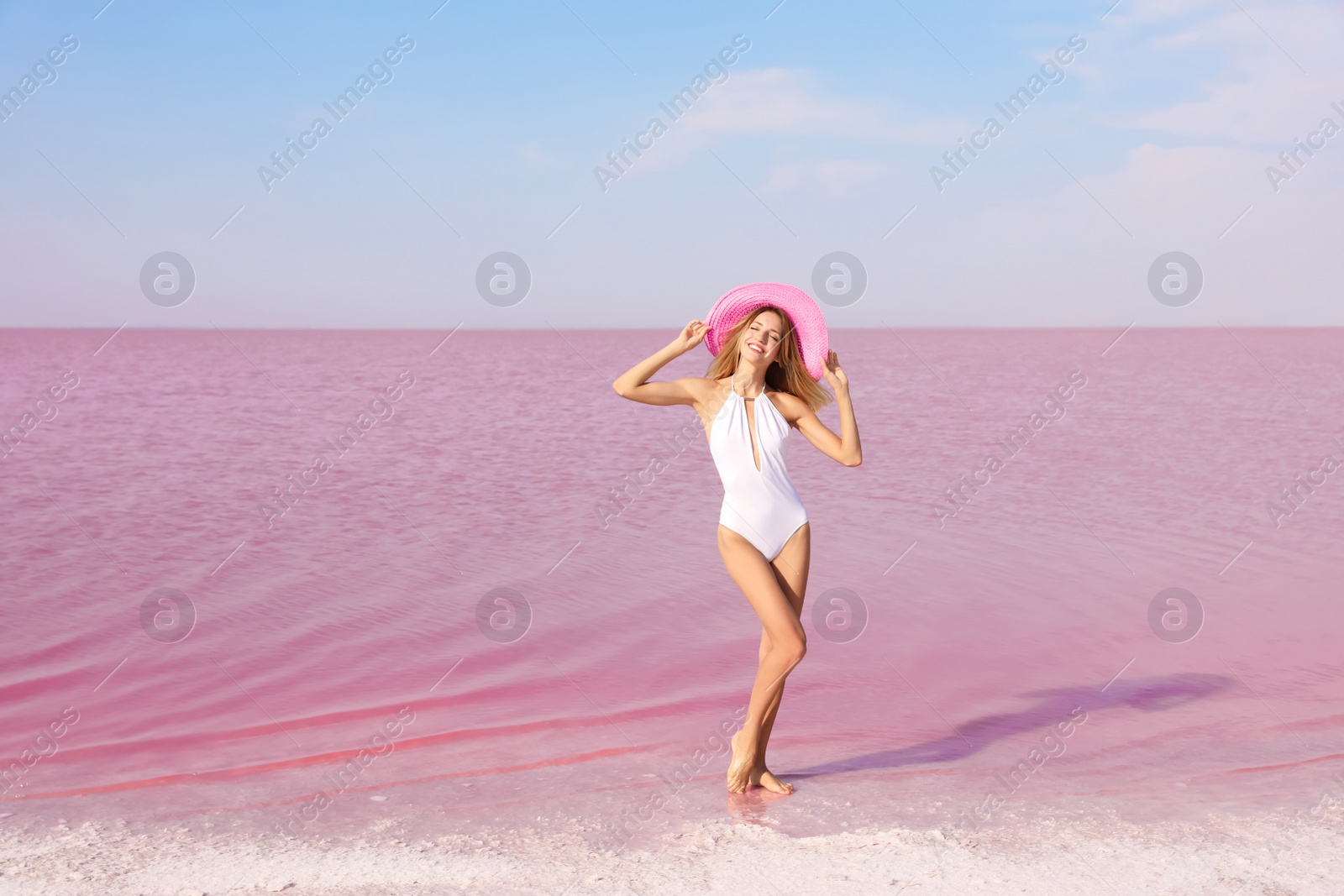 Photo of Beautiful woman in swimsuit posing near pink lake on sunny day