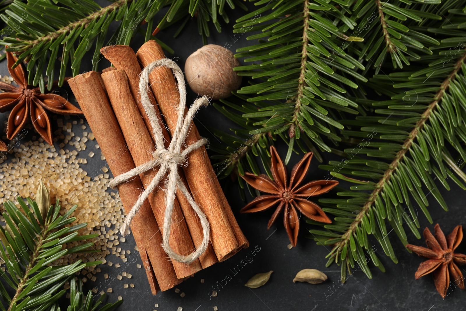 Photo of Different spices, nut and fir branches on gray table, flat lay