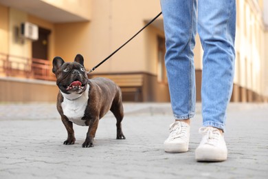 Woman walking with cute French Bulldog outdoors, closeup