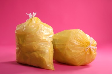 Trash bags full of garbage on pink background