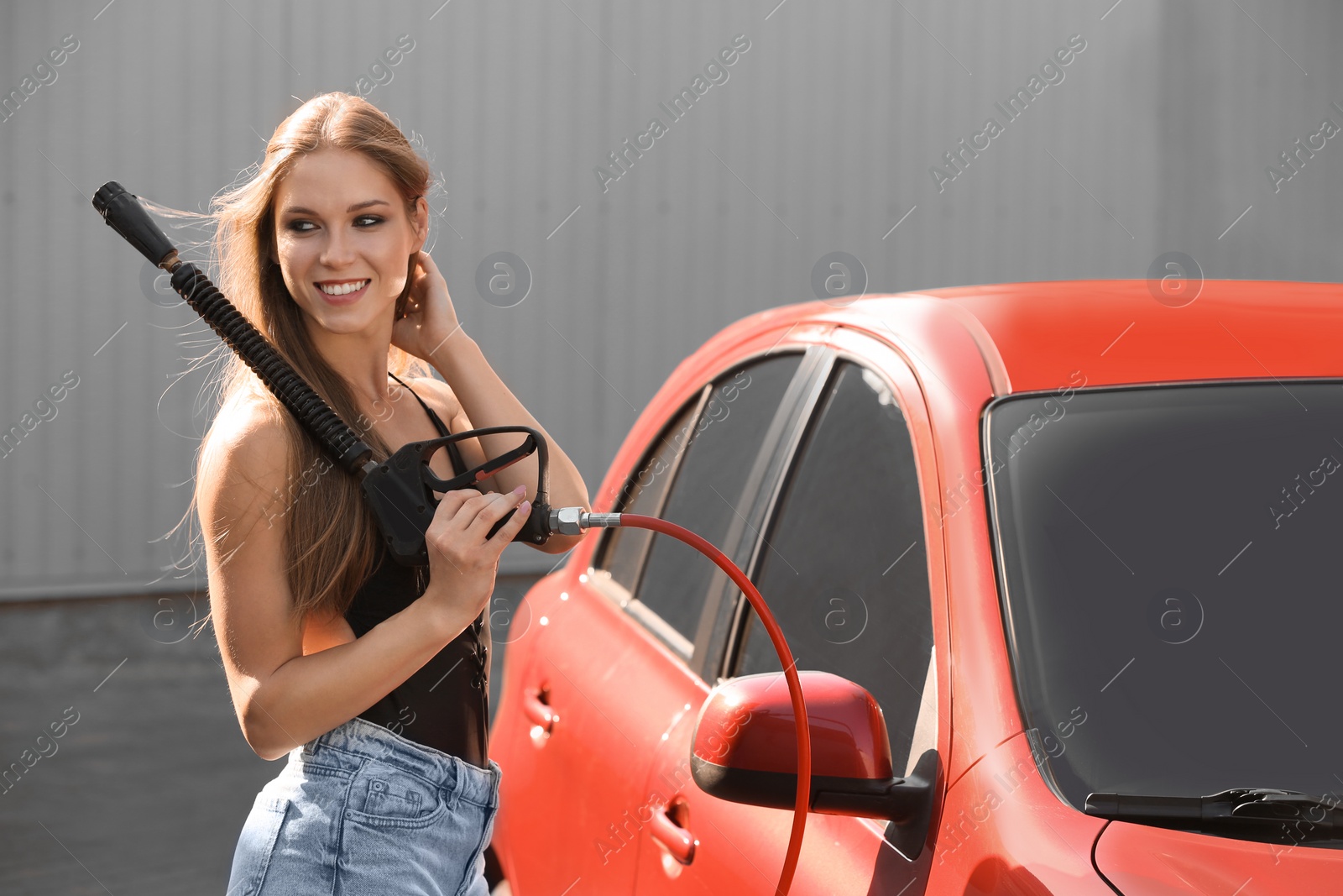 Photo of Young woman with high pressure water jet at car wash