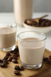 Coffee cream liqueur in glasses and beans on table, closeup