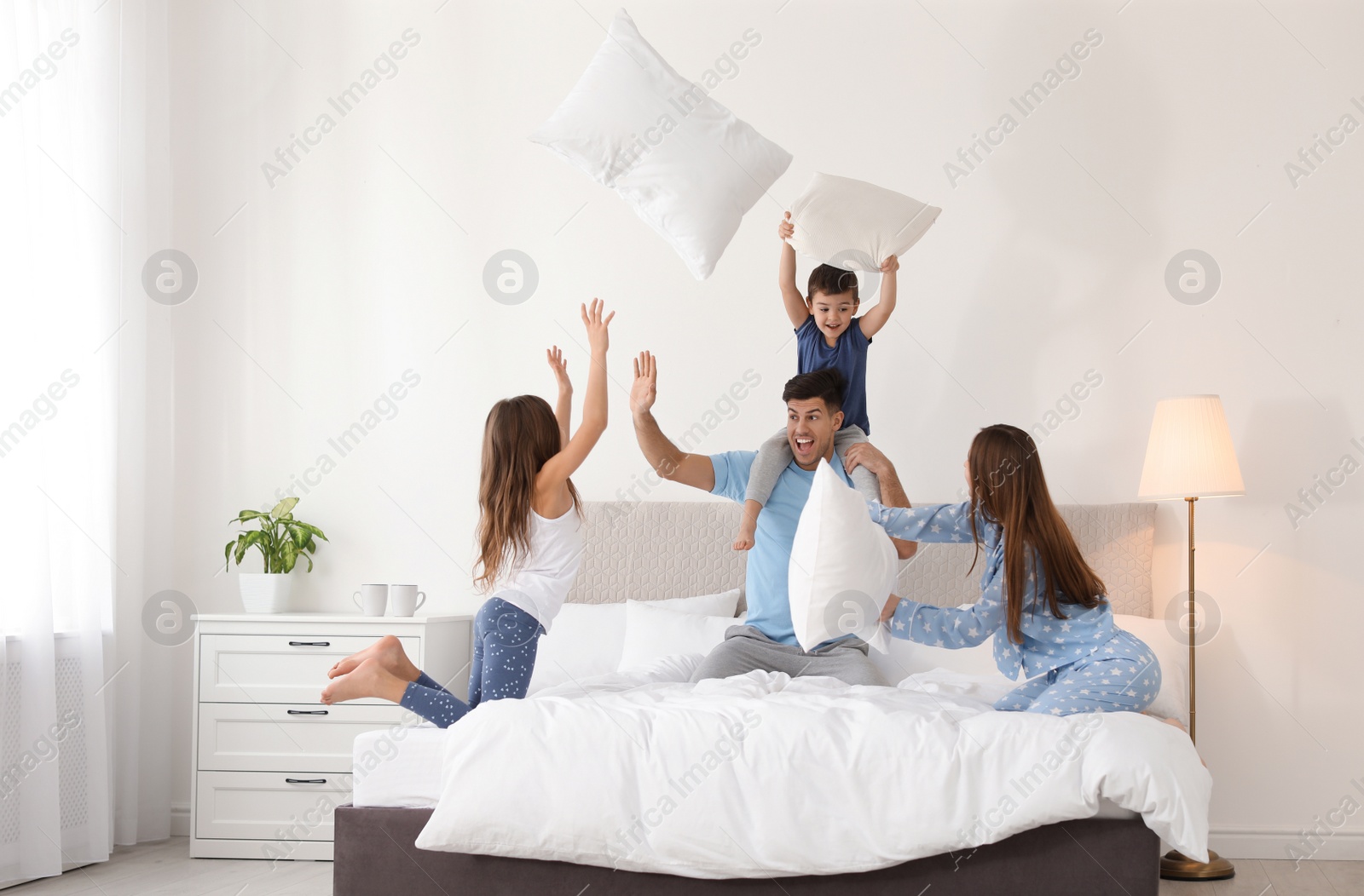 Photo of Happy family having pillow fight in bedroom