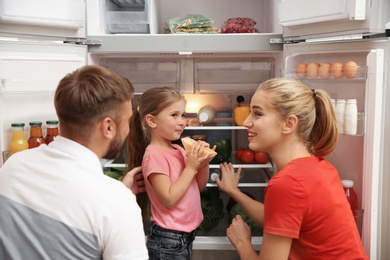 Young family choosing food in refrigerator at home