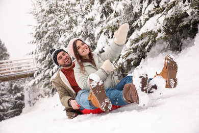 Photo of Couple having fun and sledding on snow. Winter vacation