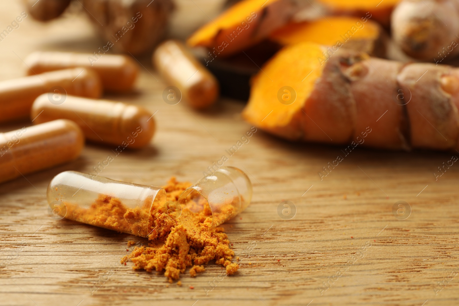 Photo of Aromatic turmeric powder and pills on wooden table, closeup with space for text