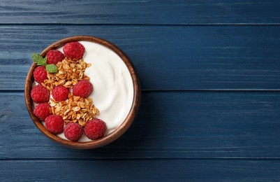 Photo of Bowl of tasty yogurt with raspberries and muesli served on blue wooden table, top view. Space for text