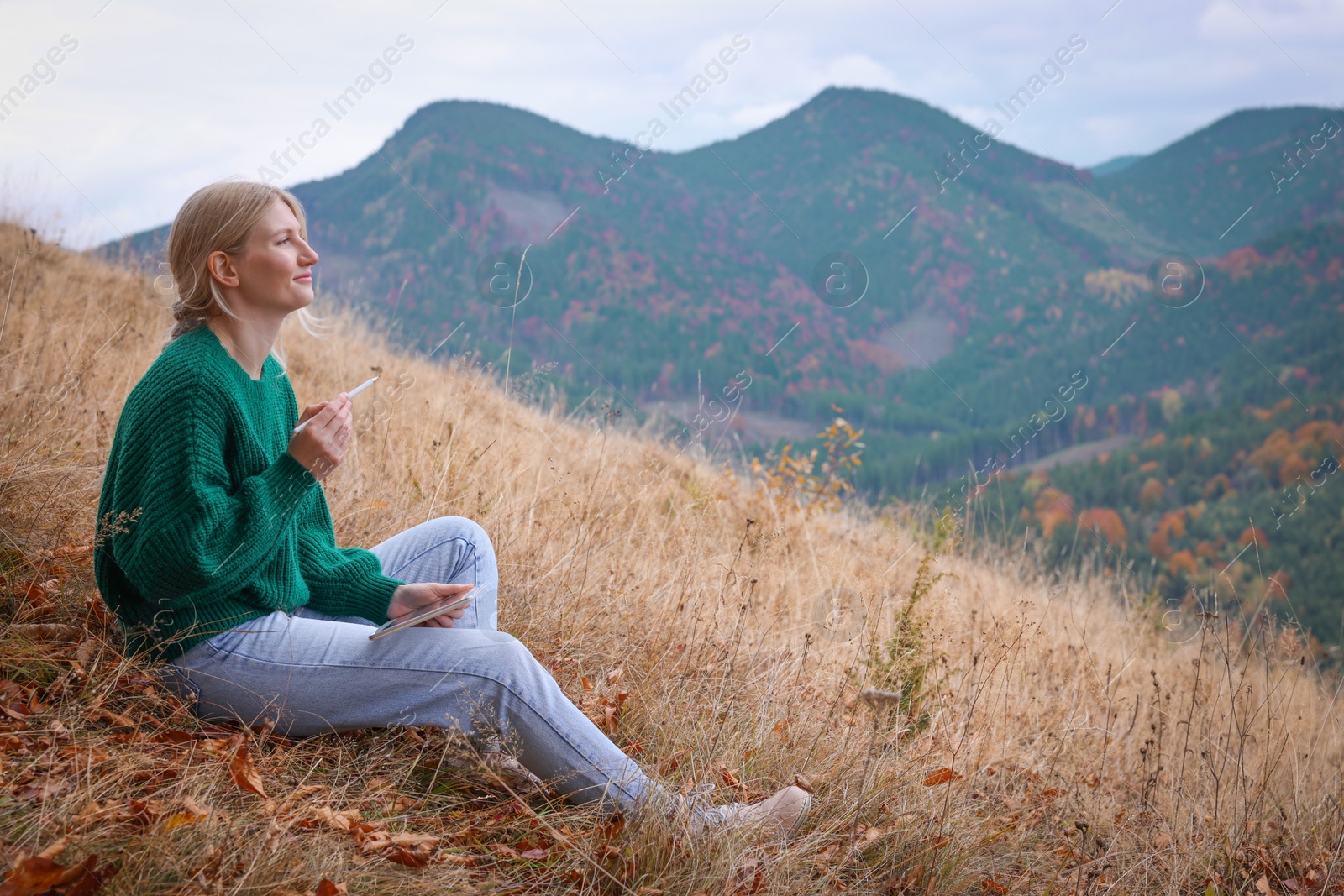 Photo of Young woman drawing on tablet in mountains, space for text