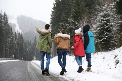 Photo of Group of friends walking near snowy forest. Winter vacation