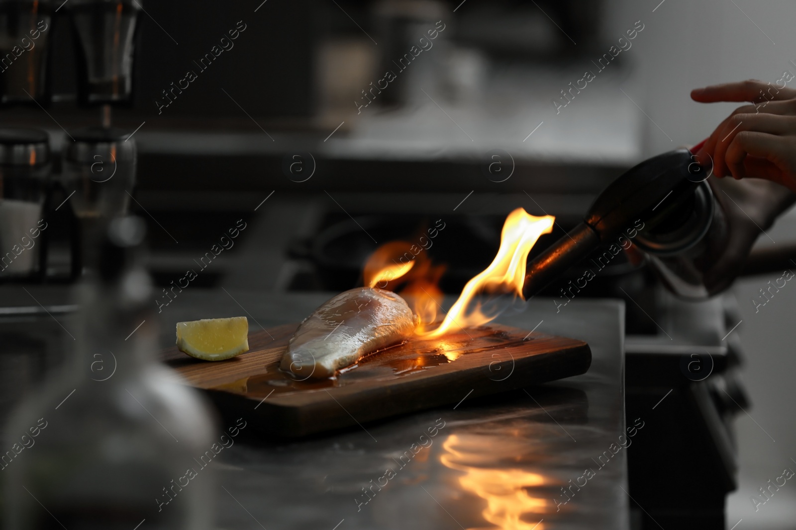 Photo of Female chef cooking chicken fillet with manual gas burner in restaurant kitchen, closeup