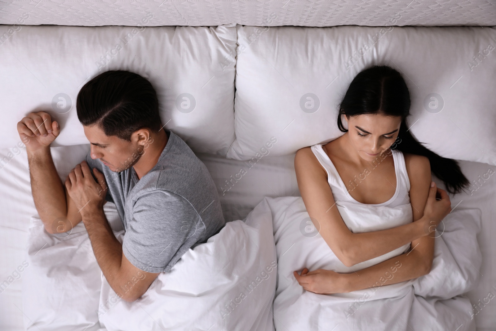 Photo of Unhappy couple with relationship problems after quarrel in bed, top view