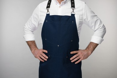 Photo of Man wearing kitchen apron on grey background, closeup. Mockup for design