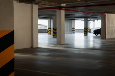 Photo of Open car parking garage, focus on column with warning stripes
