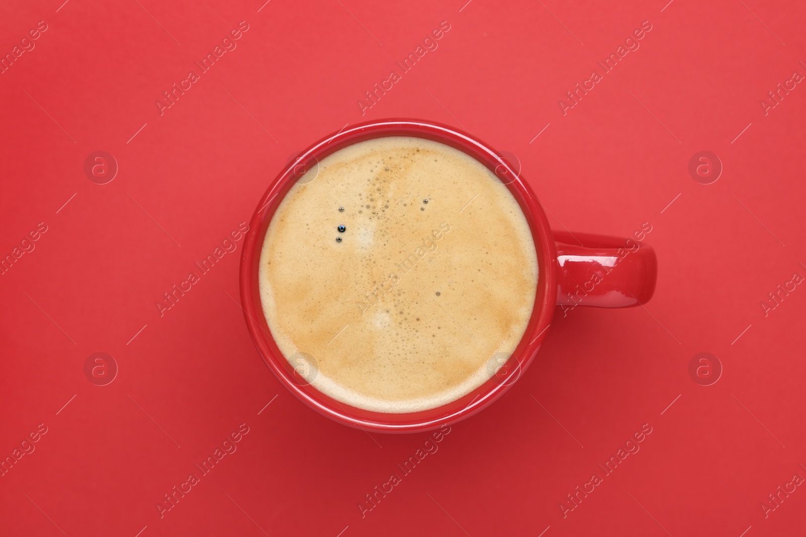 Photo of Cup of aromatic coffee on red background, top view