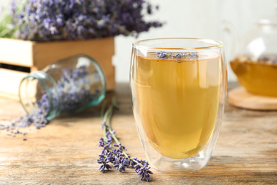 Photo of Fresh delicious tea with lavender in glass on wooden table
