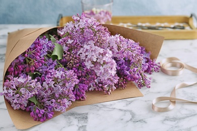 Photo of Beautiful blossoming lilac on table. Spring flowers