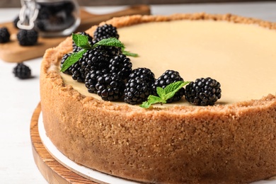 Photo of Delicious cheesecake decorated with blackberries on table