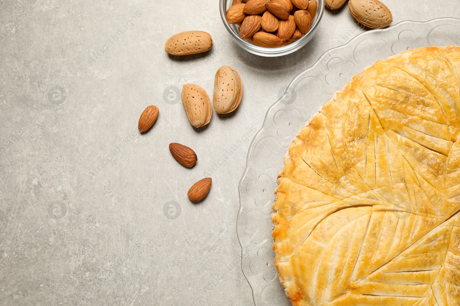 Photo of Traditional galette des rois and almonds on grey table, flat lay. Space for text