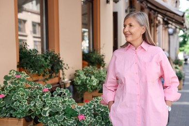 Happy business owner near her cafe outdoors, space for text