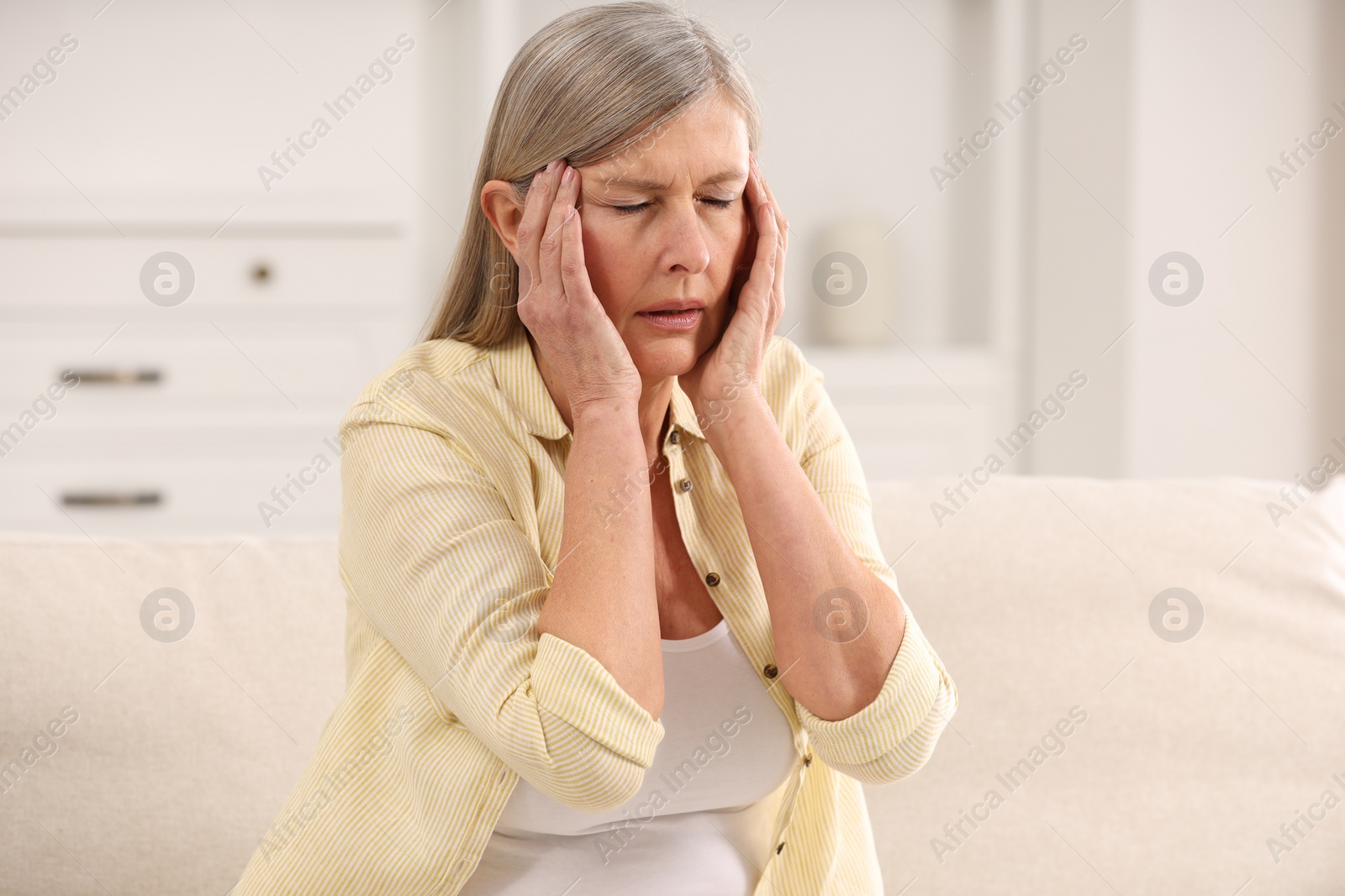 Photo of Menopause. Woman suffering from headache on sofa at home
