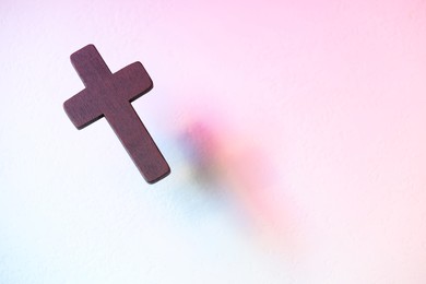 Photo of Wooden cross on textured table in color lights, above view with space for text. Religion of Christianity