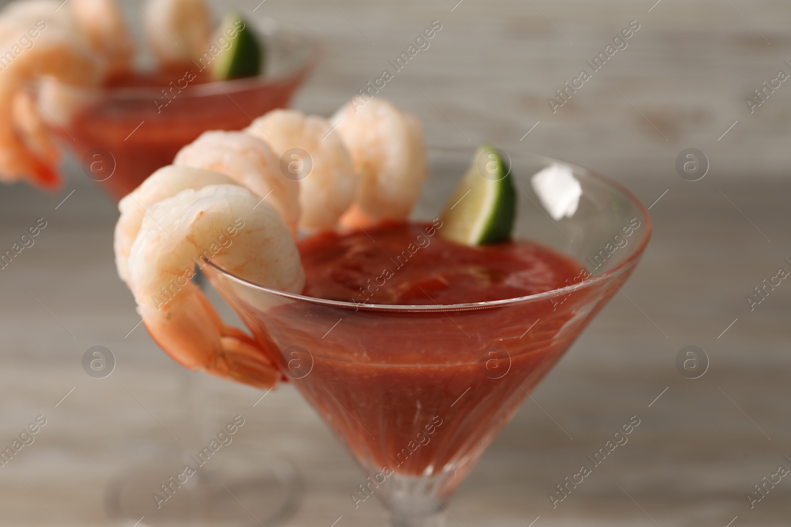 Photo of Tasty shrimp cocktail with sauce in glass on table, closeup