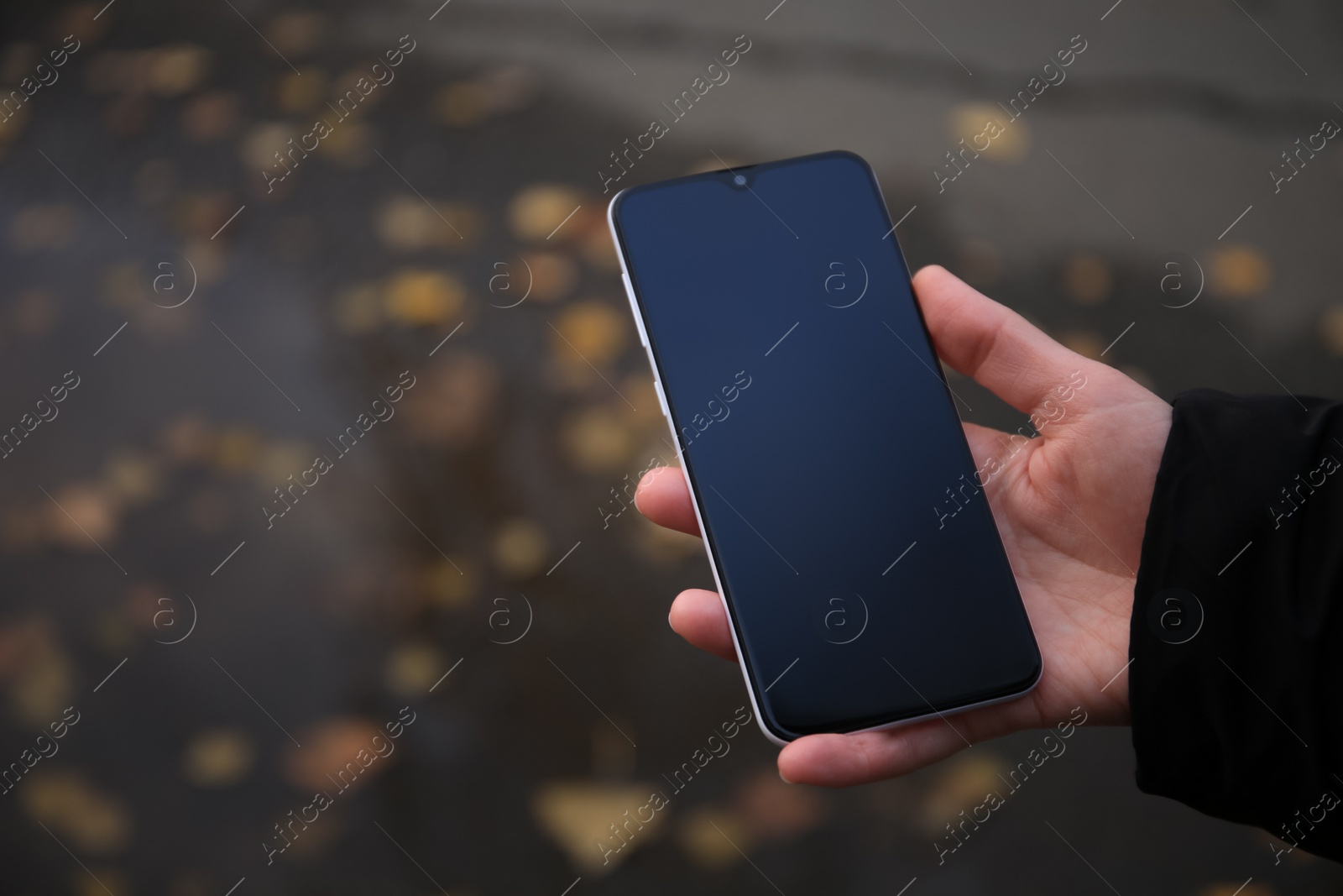 Photo of Woman holding phone outdoors on rainy day, closeup. Space or text