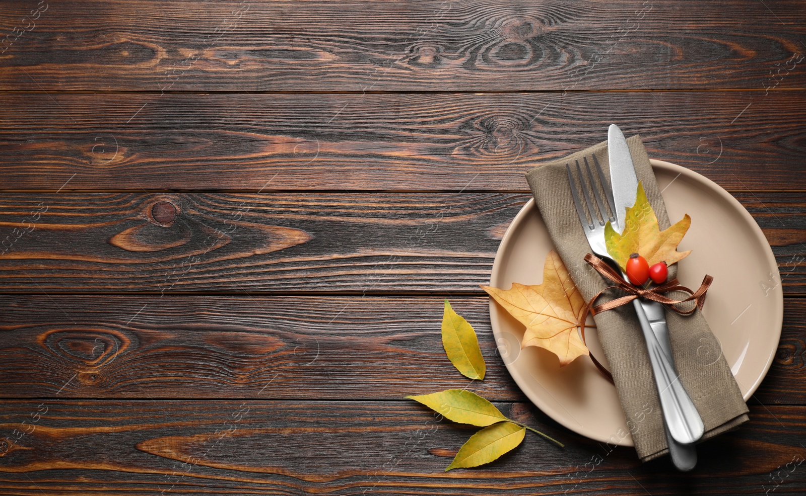 Photo of Festive table setting with autumn leaves and space for text on wooden background, flat lay. Thanksgiving Day celebration