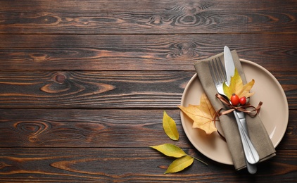 Photo of Festive table setting with autumn leaves and space for text on wooden background, flat lay. Thanksgiving Day celebration
