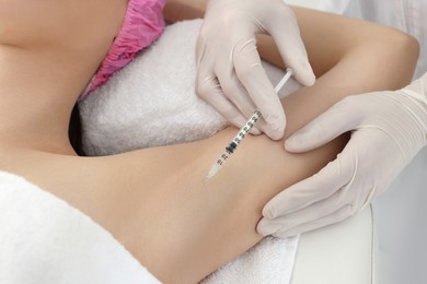 Photo of Cosmetologist injecting young woman's armpit, closeup. Treatment of hyperhidrosis