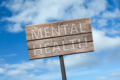 Image of Wooden sign with phrase Mental Health against blue sky on sunny day