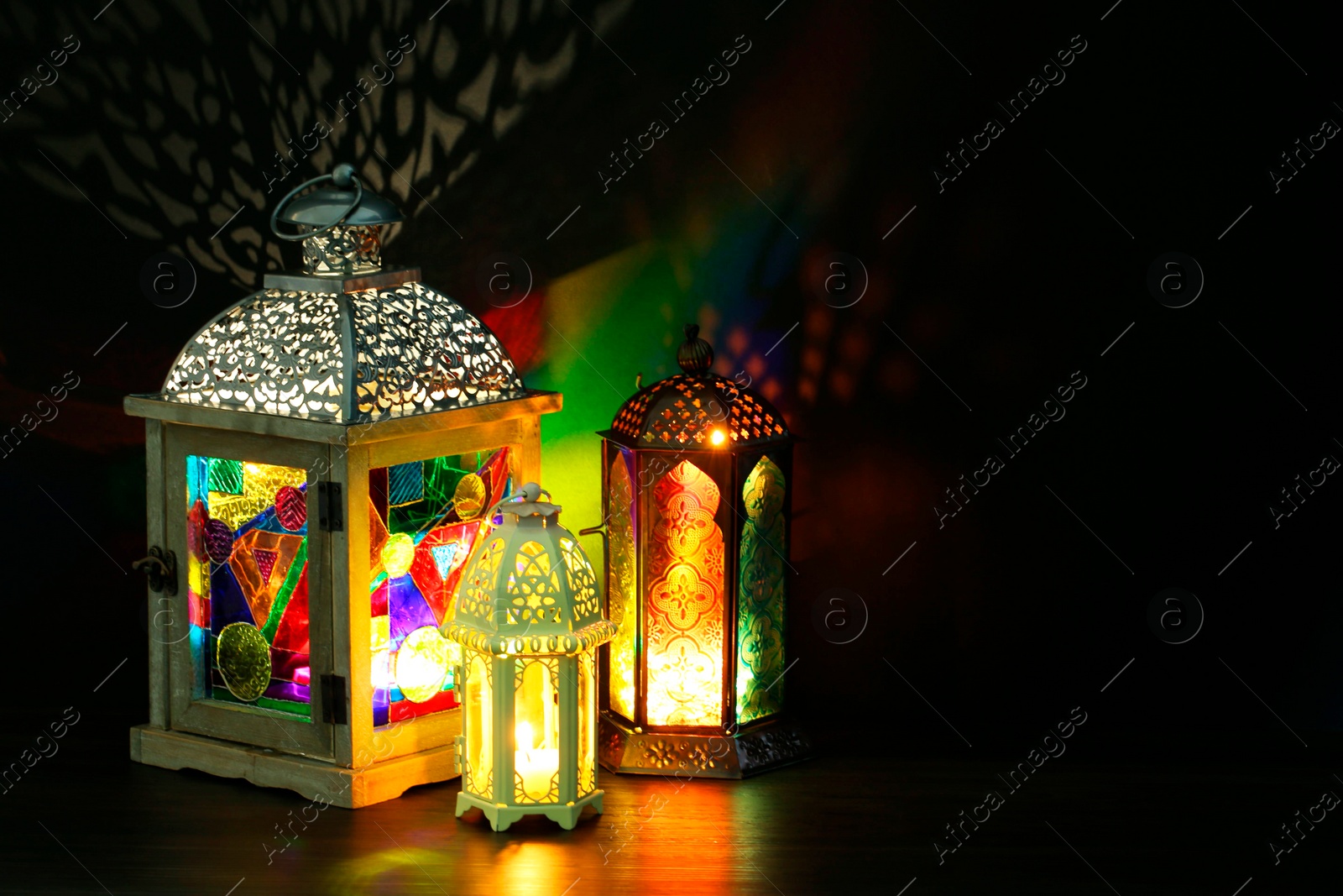 Photo of Decorative Arabic lanterns on table against dark background. Space for text