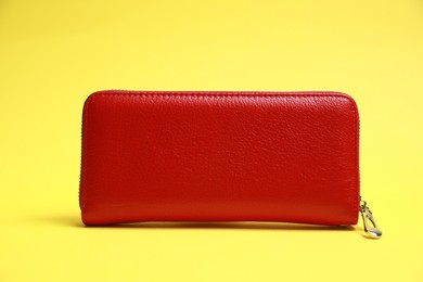Photo of Stylish red leather purse on yellow background