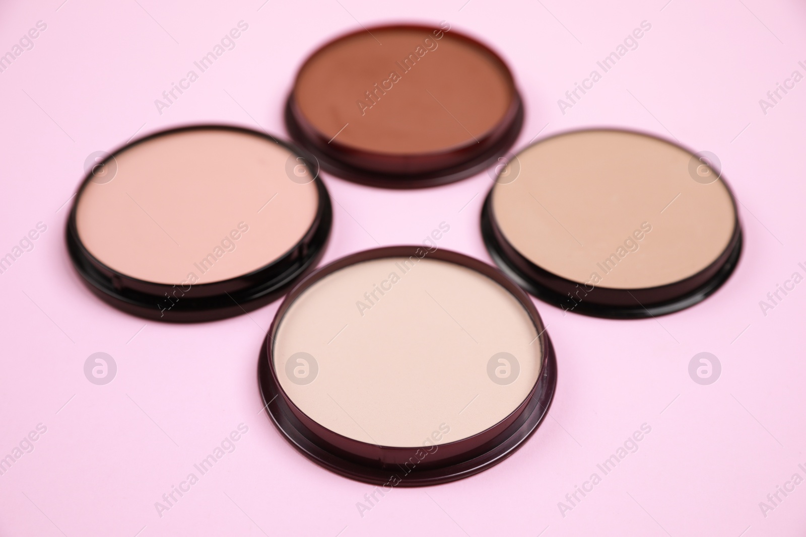 Photo of Different face powders on pink background. Decorative cosmetic