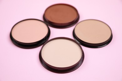 Different face powders on pink background. Decorative cosmetic