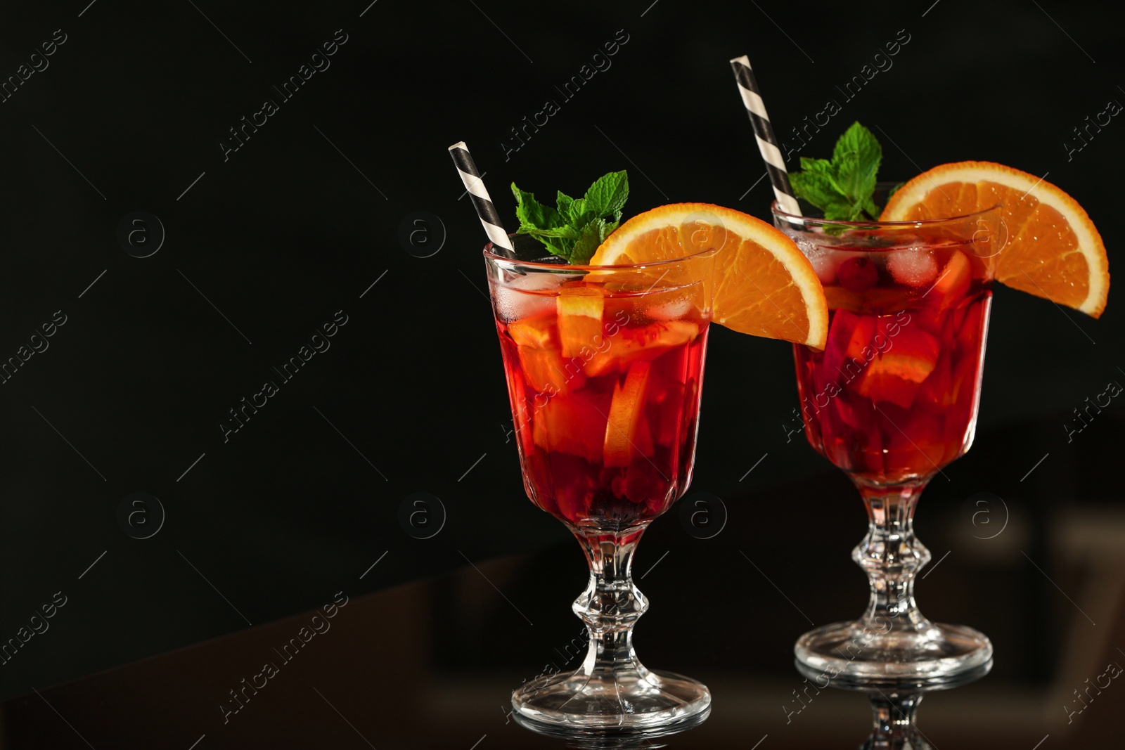 Photo of Delicious sangria cocktail on black table in bar. Space for text