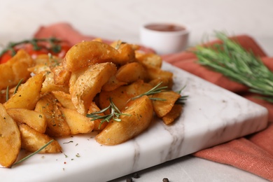 Photo of Marble board with baked potatoes and rosemary on table, closeup