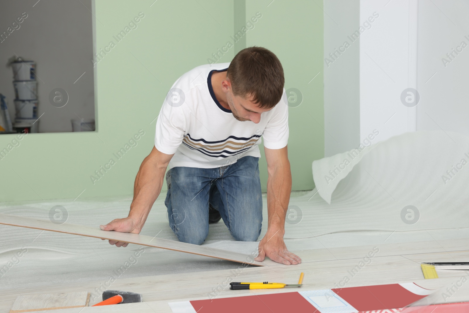 Photo of Man installing new laminate flooring in room