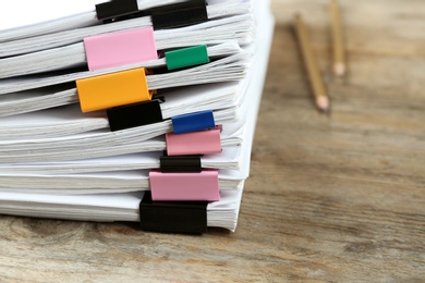 Photo of Stack of documents with colorful binder clips on wooden table, closeup