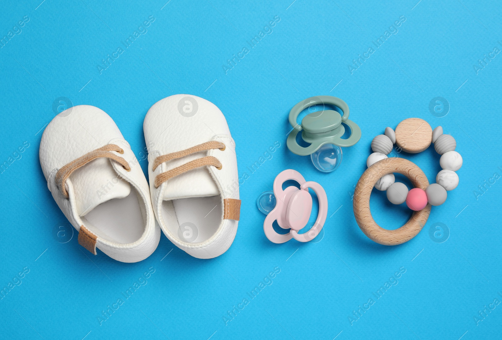 Photo of Flat lay composition with pacifiers and other baby stuff on light blue background