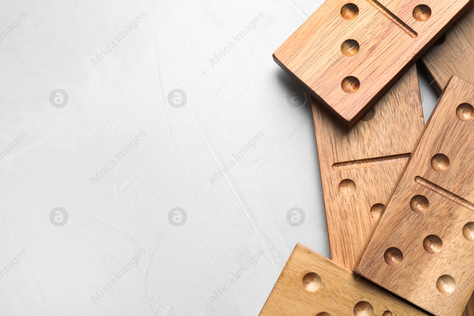 Photo of Wooden domino tiles on light grey table, flat lay. Space for text