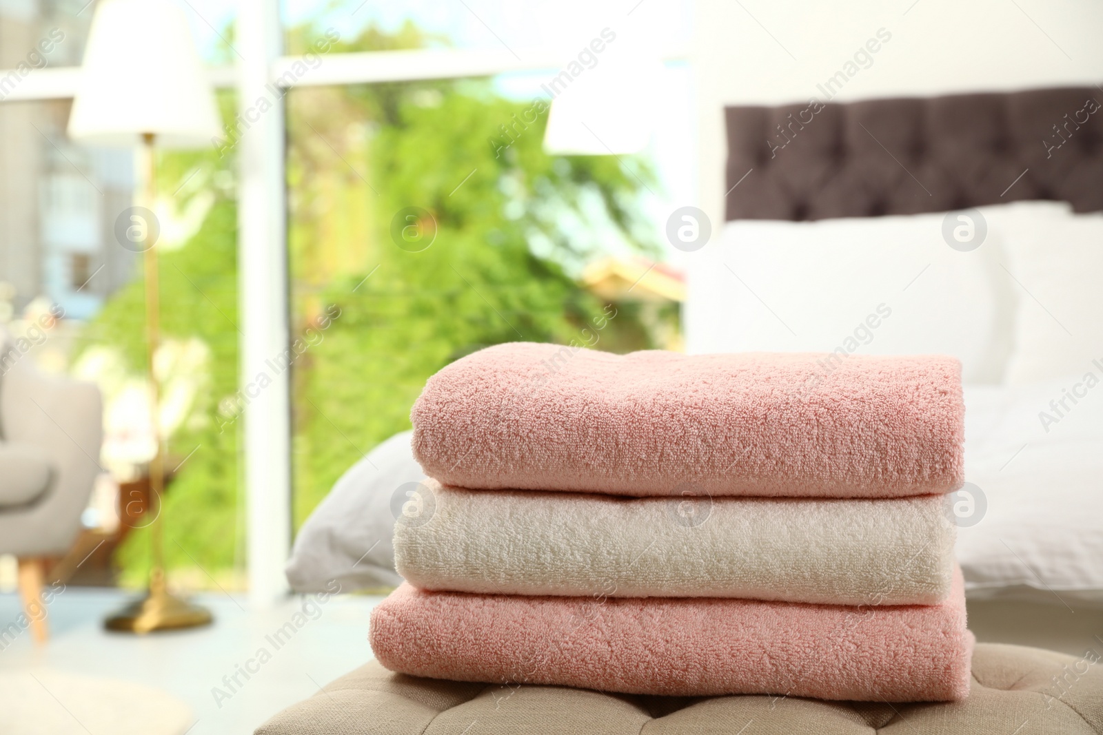 Photo of Stack of soft clean terry towels on bedside bench. Space for text